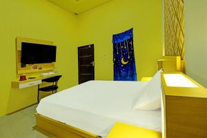 Dormitorio con cama, escritorio y TV en OYO 91857 Callista Homestay, en Bonthain