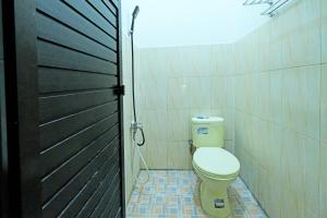 baño con aseo y puerta negra en OYO 91857 Callista Homestay, en Bonthain