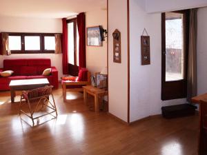a living room with a red couch and a table at Appartement Les Orres, 2 pièces, 8 personnes - FR-1-322-191 in Les Orres