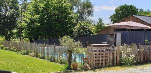 a wooden fence with an umbrella in a yard at Gîte le talus in Amanlis