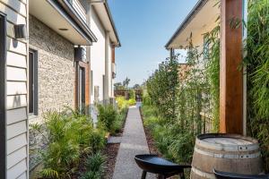 a walkway between two buildings with chairs and a barrel at Earimil Villas - Waterfront in Mount Eliza