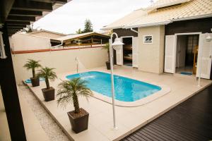 una piscina con palmeras en un patio trasero en Casa top! Piscina, sinuca, 350 mts do mar, en Palhoça
