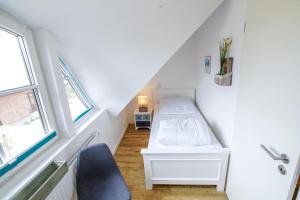 a white room with a bed in the attic at Ferienwohnung 11 "Gut Tossens" in Tossenserdeich