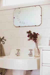 a bathroom with a white sink and a mirror at Quaint and intimate 1-bed seaside cottage in Bridport