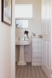 Baño blanco con lavabo y espejo en Quaint and intimate 1-bed seaside cottage, en Bridport