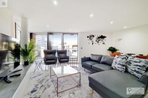 a living room with a blue couch and chairs at Stylish Three Bedroom Apartment by London ExCeL in London