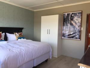a bedroom with a white bed and a picture on the wall at Radies Bed and Breakfast in Cofimvaba