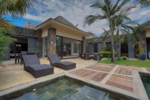 un patio trasero con piscina y una casa en Balinea Villas, en Pereybere