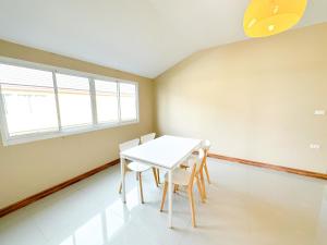 een eetkamer met een witte tafel en stoelen bij The Island Resort in Bangkok