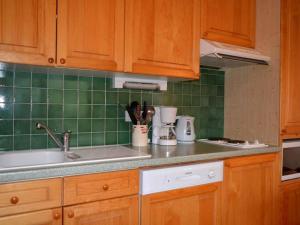 a kitchen with wooden cabinets and green tiles at Appartement Le Grand-Bornand, 2 pièces, 5 personnes - FR-1-241-147 in Le Grand-Bornand