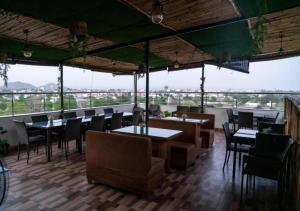 a restaurant with tables and chairs and a view at Hotel Agnija Udaipur in Udaipur