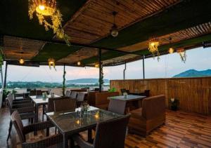a restaurant with tables and chairs and a view of the mountains at Hotel Agnija Udaipur in Udaipur