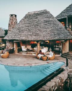 a villa with a thatched roof and a swimming pool at Olarro Plains in Masai Mara