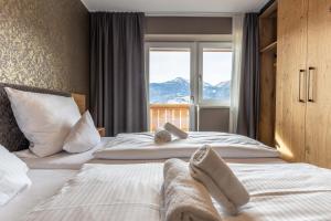 two beds in a hotel room with a window at Zugspitz Residence Ehrwald in Ehrwald