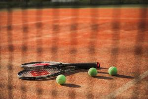 una raqueta de tenis y cuatro pelotas de tenis en una pista de tenis en Holiday Club Saimaa Apartments, en Imatra