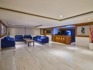 a lobby with blue chairs and a table and a tv at Essentia Premier Hotel Chennai OMR in Chennai