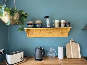 a counter with a shelf with cups and appliances on it at Steinholt, charming & just renovated apartment ! in Seyðisfjörður