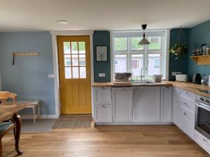 a kitchen with white cabinets and a yellow door at Steinholt, charming & just renovated apartment ! in Seyðisfjörður