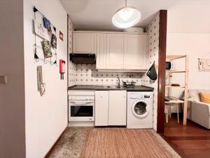 a small kitchen with white cabinets and a washer and dryer at Studio Gerês in Geres