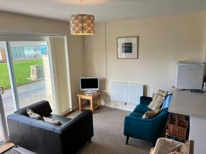 a living room with two couches and a television at 2 Bedroom Bungalow SV58, Seaview, Isle of Wight Free Wi-Fi in Seaview