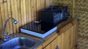 un four micro-ondes assis sur un comptoir à côté d'un évier dans l'établissement The Beach House Carabao Island, à San Jose