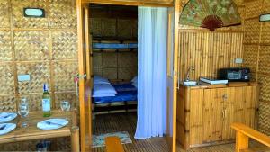 a room with a bunk bed and a table with glasses at The Beach House Carabao Island in San Jose