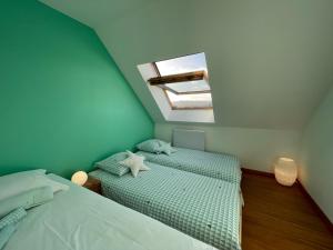 sypialnia na poddaszu z 2 łóżkami i świetlikiem w obiekcie Villa Balaou - Vue mer exceptionnelle - w mieście Urville-Nacqueville