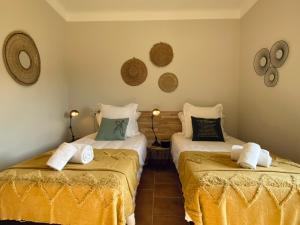 - une chambre avec 2 lits avec des draps jaunes dans l'établissement Mas de Veyras - Gîtes 5 étoiles en Ardèche, à Lachapelle-sous-Aubenas