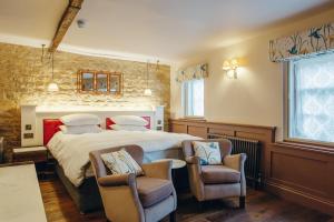 a bedroom with a large bed and two chairs at Crown Hotel in Stamford