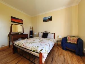 1 dormitorio con cama, silla y espejo en Ruby's Cottage Farm Stay en Port Arthur