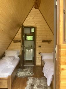 a room with two beds in a wooden cabin at Căsuța - La Țanc in Martinie