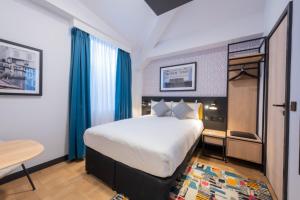 una habitación de hotel con una cama grande y una mesa en The Wesley Camden Town, en Londres