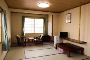 ein Wohnzimmer mit einem TV, einem Tisch und Stühlen in der Unterkunft Hotel Tsustujisou in Kitami