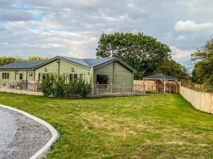 a green house with a fence and a yard at Beautiful 3-Bed Luxury Private Lodge in York in York