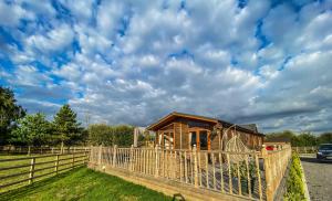 a wooden cabin in a field with a fence at Immaculate 3-Bedroom Private Lodge near York in York