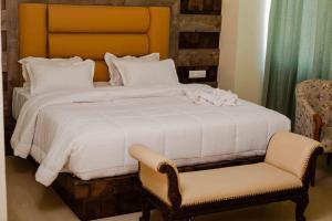 a bedroom with a large white bed and a chair at Hotel Grand Lotus in Dimāpur