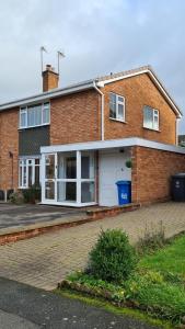 a brick house with a white garage at Woodstock by Spires Accommodation a uniquely Retro place to stay near Wolverhampton in Codsall