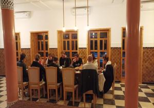 un gruppo di persone seduti intorno a un tavolo in una stanza di Kasr Tin Hinane a Merzouga