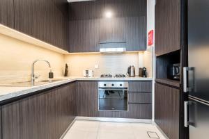 uma cozinha com armários de madeira e um forno com placa de fogão em Luxury StayCation - Fancy Apartment Connected To Burj Khalifa em Dubai