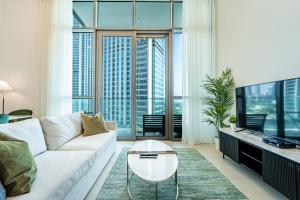 uma sala de estar com um sofá branco e uma televisão em Luxury StayCation - Fancy Apartment Connected To Burj Khalifa em Dubai
