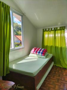 a small bed in a room with a window at Small House - Baguio in Baguio
