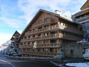 メリベルにあるAppartement 3 pièces avec balcon, parking et wifi, proche du centre de Méribel, pour 7 personnes - FR-1-180-211の雪に覆われた木製バルコニー付きの大きな建物