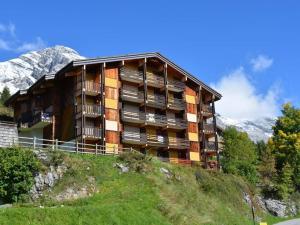 ein Gebäude auf einem Hügel mit Bergen im Hintergrund in der Unterkunft Studio Le Grand-Bornand, 1 pièce, 4 personnes - FR-1-241-19 in Le Grand-Bornand