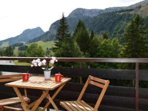a wooden table and chairs on a balcony with mountains at Appartement Le Grand-Bornand, 1 pièce, 4 personnes - FR-1-241-126 in Le Grand-Bornand