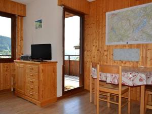 Zimmer mit einem Schreibtisch, einem TV und einem Tisch mit Stühlen. in der Unterkunft Studio Le Grand-Bornand, 1 pièce, 4 personnes - FR-1-241-109 in Le Grand-Bornand