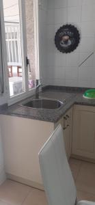 a kitchen with a sink and a white chair at Apartamentos Puerto de Aguiño in Couso