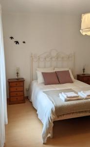 een slaapkamer met een groot wit bed met 2 vleermuizen aan de muur bij Casa Domingues Guest House in Caldas da Rainha