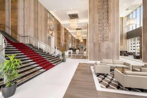 a lobby of a building with stairs and chairs at Wyndham Doha West Bay in Doha