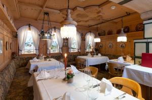 グリンデルワルトにあるロマンティック ホテル シュヴァイツァーホフの白いテーブルと椅子、シャンデリアのあるレストラン