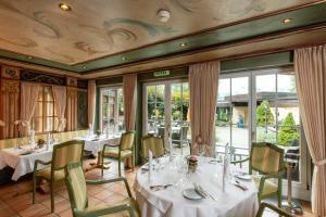 un restaurante con mesas y sillas blancas y ventanas en Romantik Hotel Schweizerhof en Grindelwald